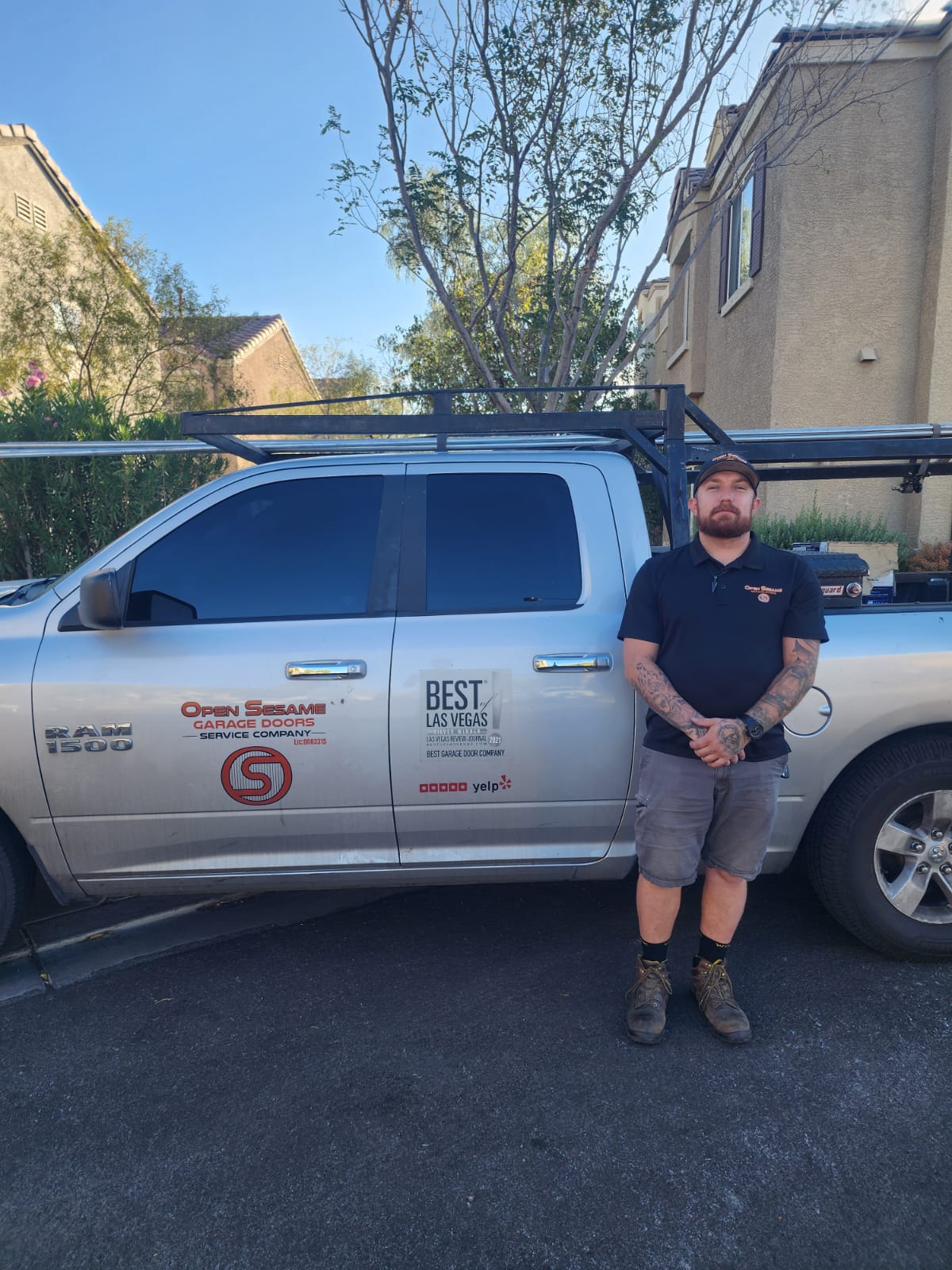 Technician standing beside an Open Sesame Garage Doors branded Ram 1500 service truck